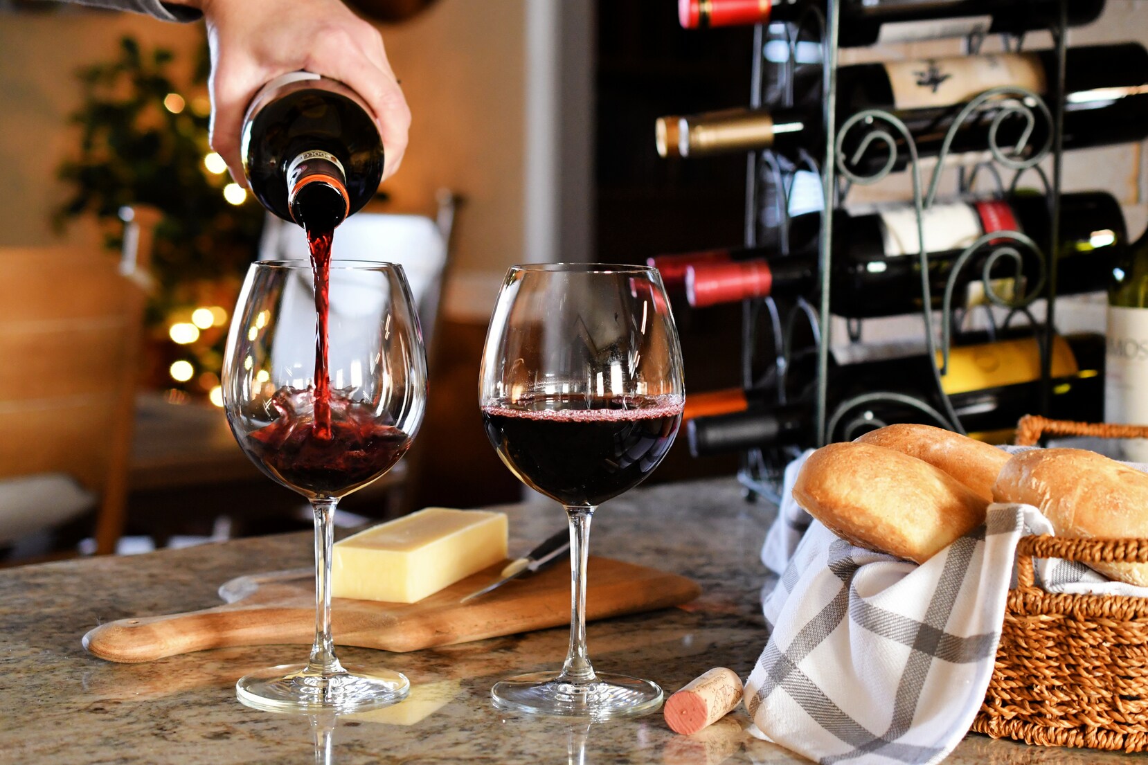 Cropped Hand Pouring Red Wine In Glass On Table