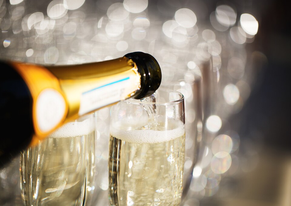 Champagne being poured into elegant flutes with a sparkling bokeh background