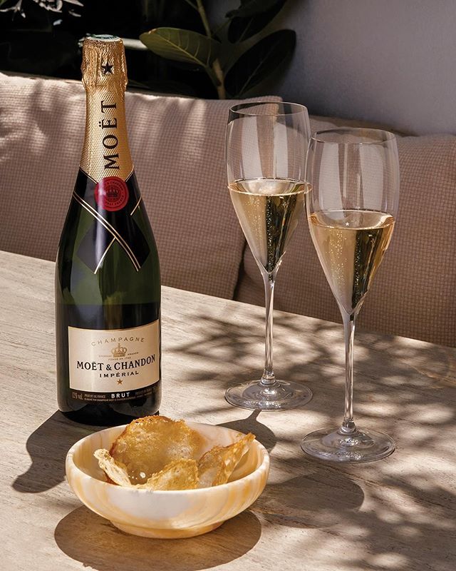 A bottle of Moët & Chandon champagne with two fluted glasses, half-filled with golden bubbly liquid