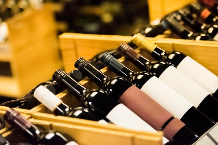 Wooden wine rack with wine bottles, labels for copy space, selective focus