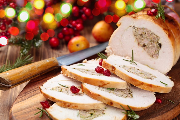 Stuffed turkey breast with pomegranate and rosemary  on cutting board.